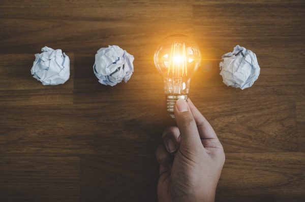 Hand choose light bulb and crumpled office paper. Concept of inspiration creative idea thinking and future technology innovation